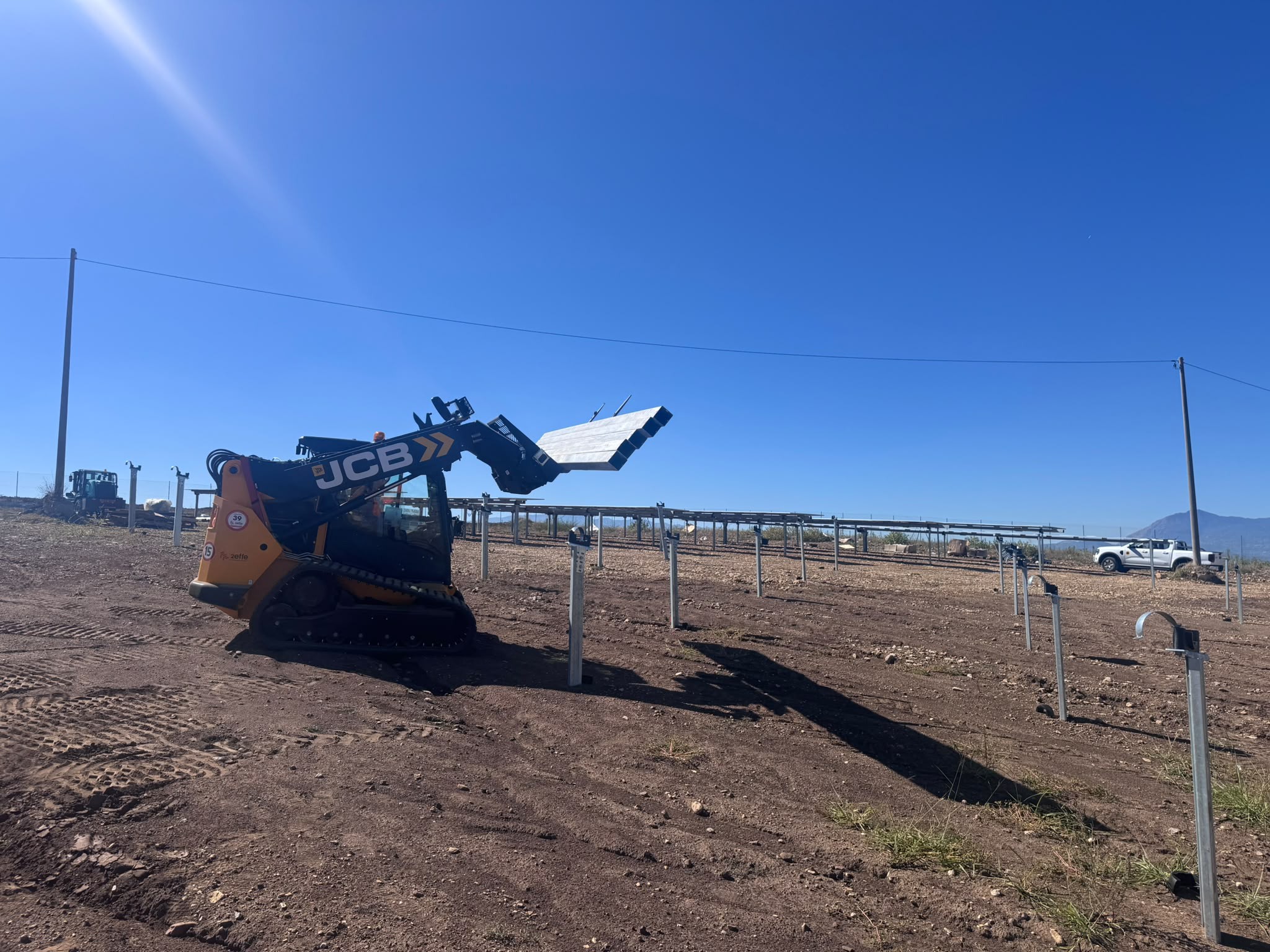 Pali infissi e mezzo d’opera in un cantiere fotovoltaico a terra
