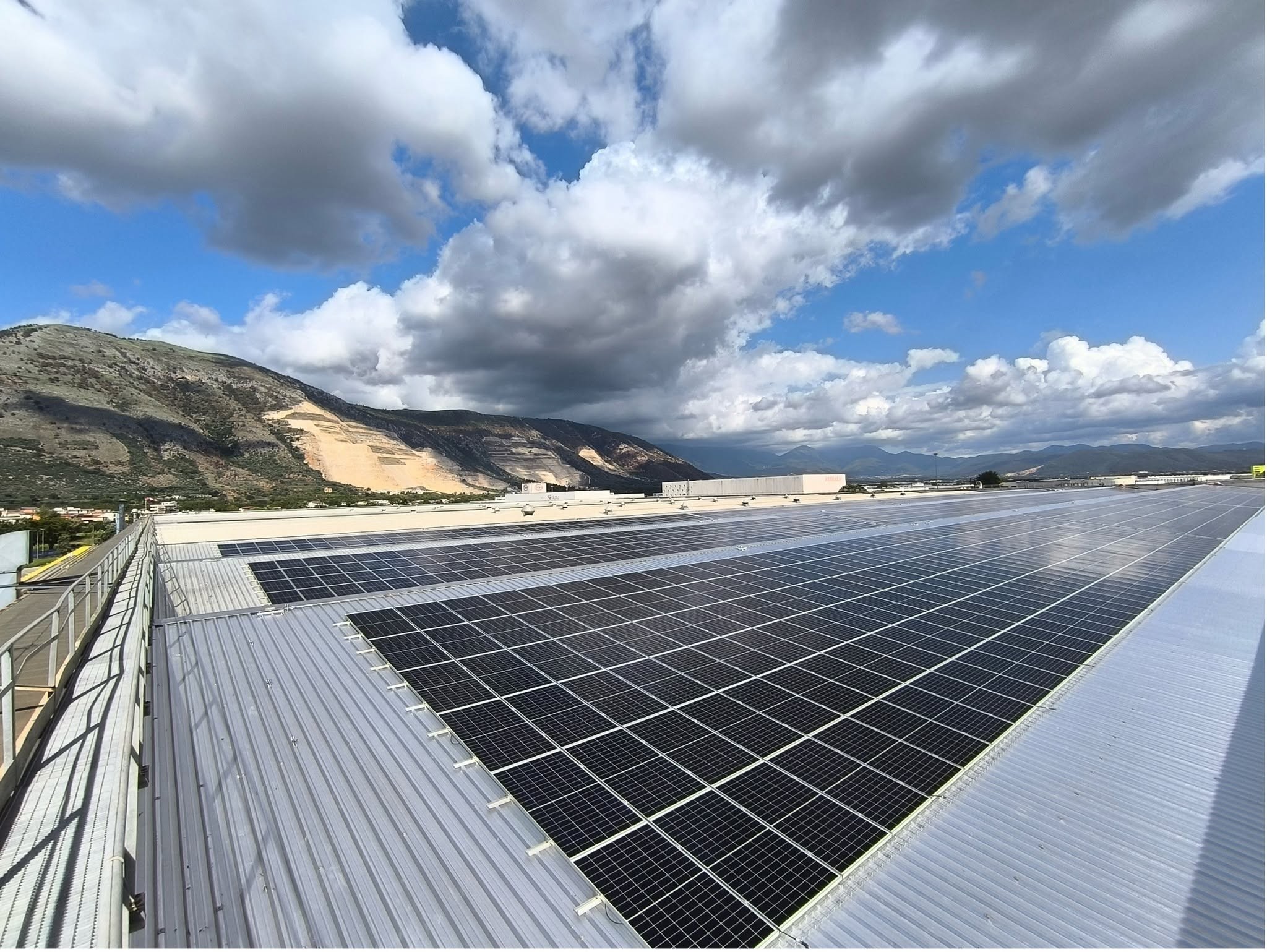Impianto fotovoltaico su una grande copertura industriale con vista sulle montagne