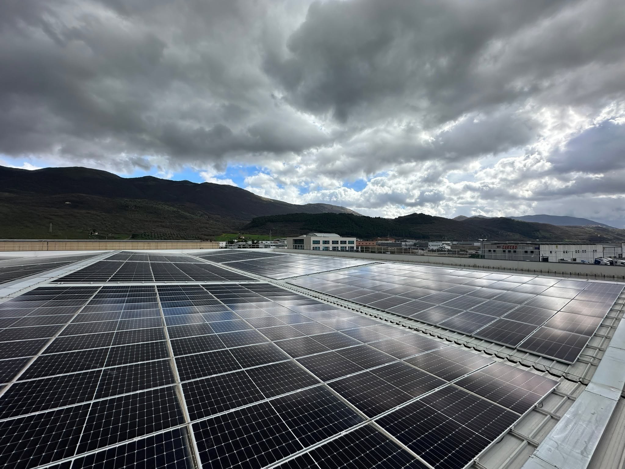 Impianto fotovoltaico su copertura industriale con vista sulle montagne